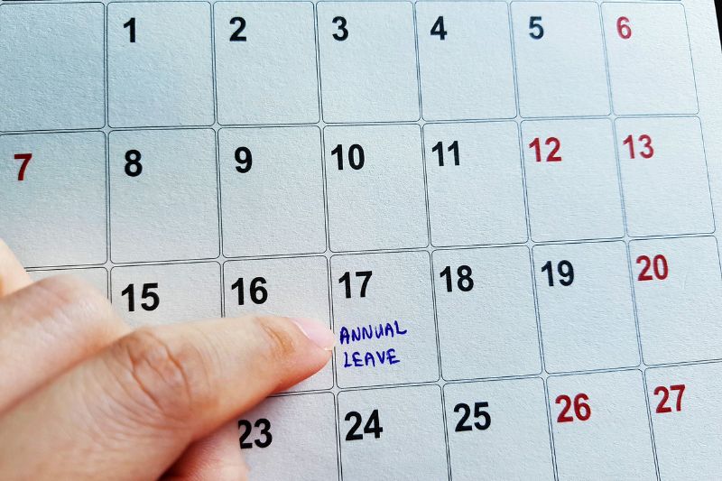 Finger pointing to a date on a white calender page on the 17th of some month with annual leave writing in blue ink